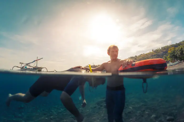 Freedivers training static breath hold in shallow water of a calm bay. Coach watching student.